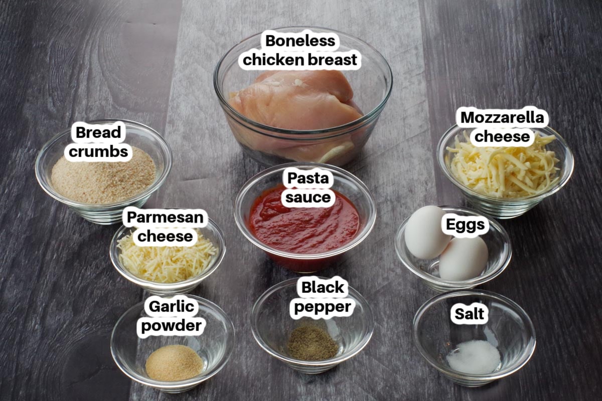 ingredients in one pan chicken parmesan in glass bowls on a faux wood surface