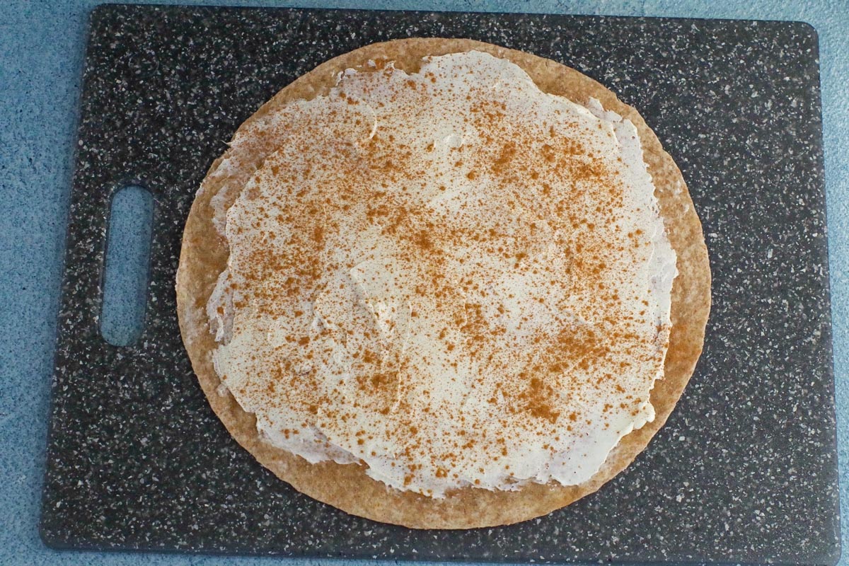 tortilla with cream cheese and cinnamon on cutting board