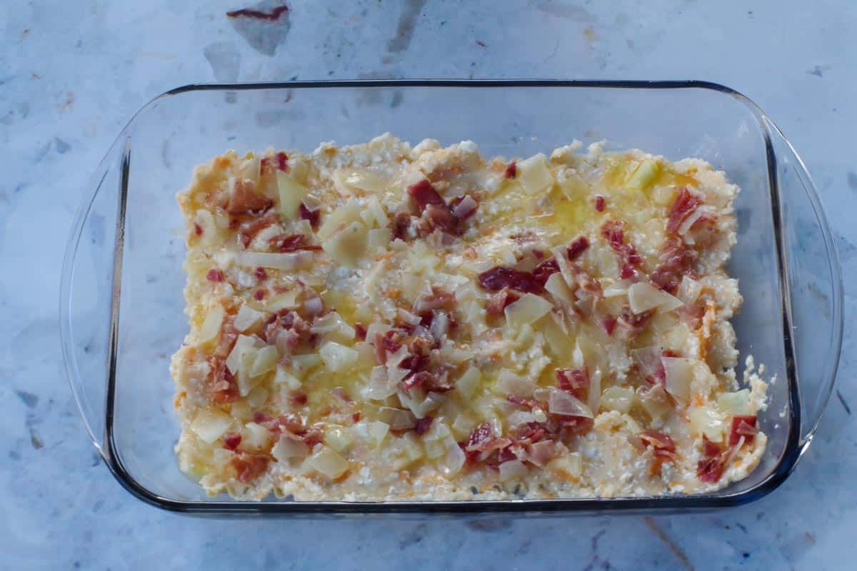onion butter and bacon mixture spread over potato layer in glass pan