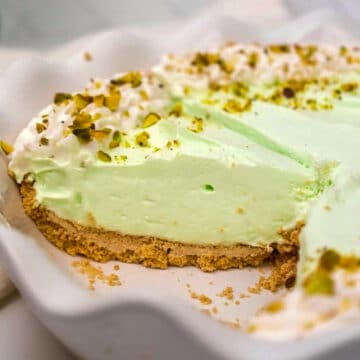 pistachio cream pie in a white pie dish with 2 pieces missing