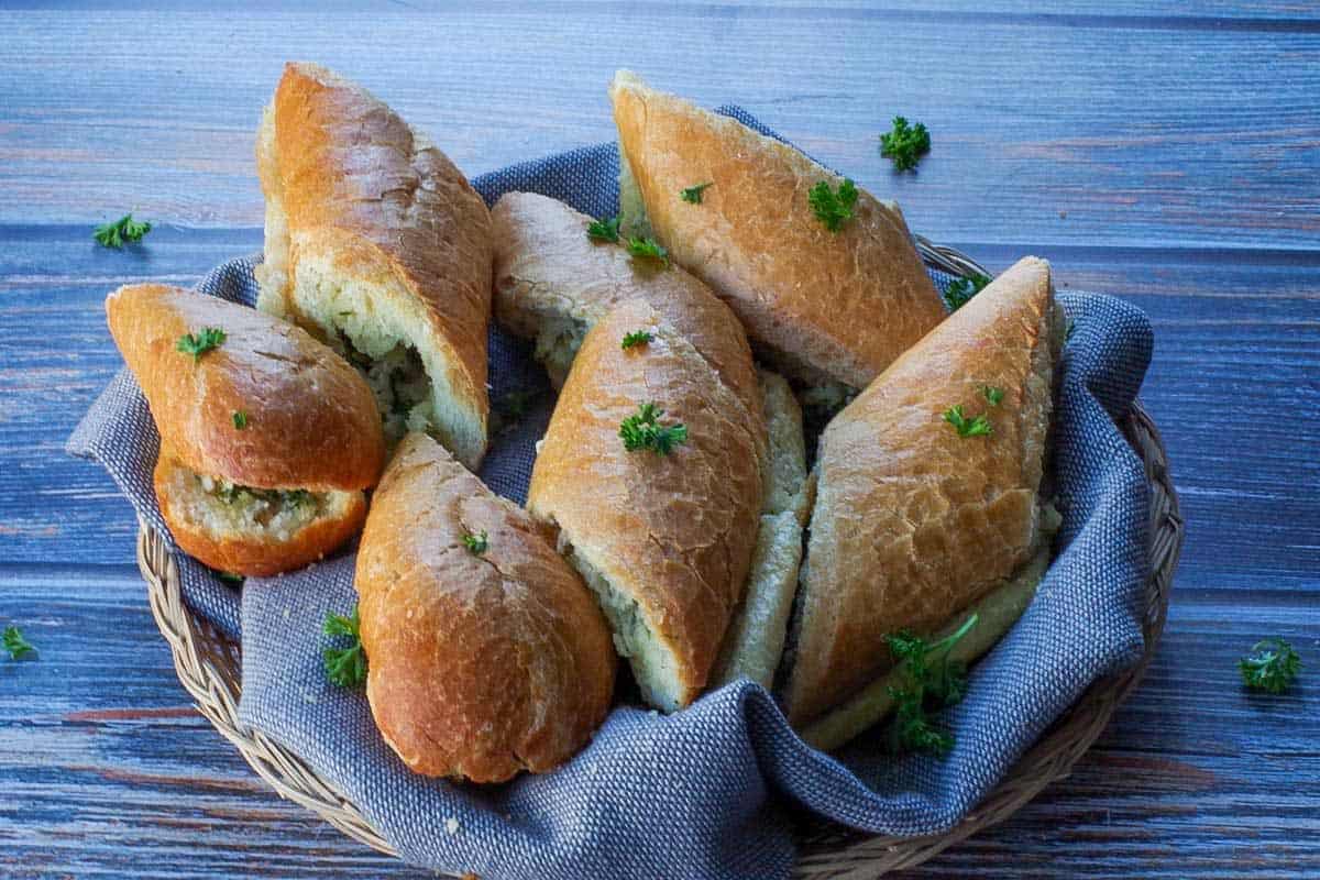 sliced baguette garlic bread in a small basket with a grey liner