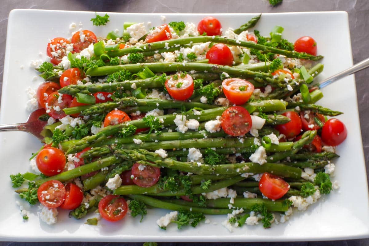 asparagus and tomato salad on a white platter