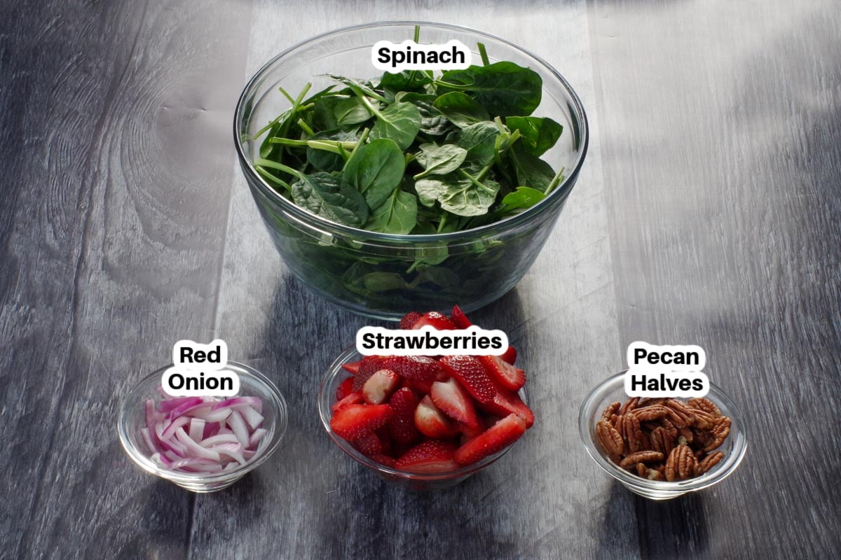ingredients in strawberry spinach pecan salad in glass bowls, labelled