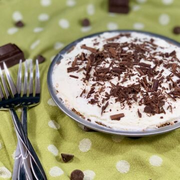 whole chocolate cream pie on green background with white polka-a -dots, with a couple of forks on the side