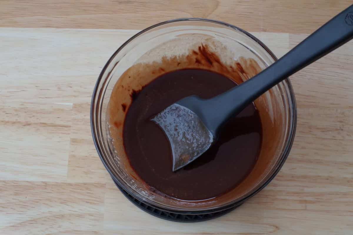 butter and chocolate melted in medium glass bowl with black spatula in bowl