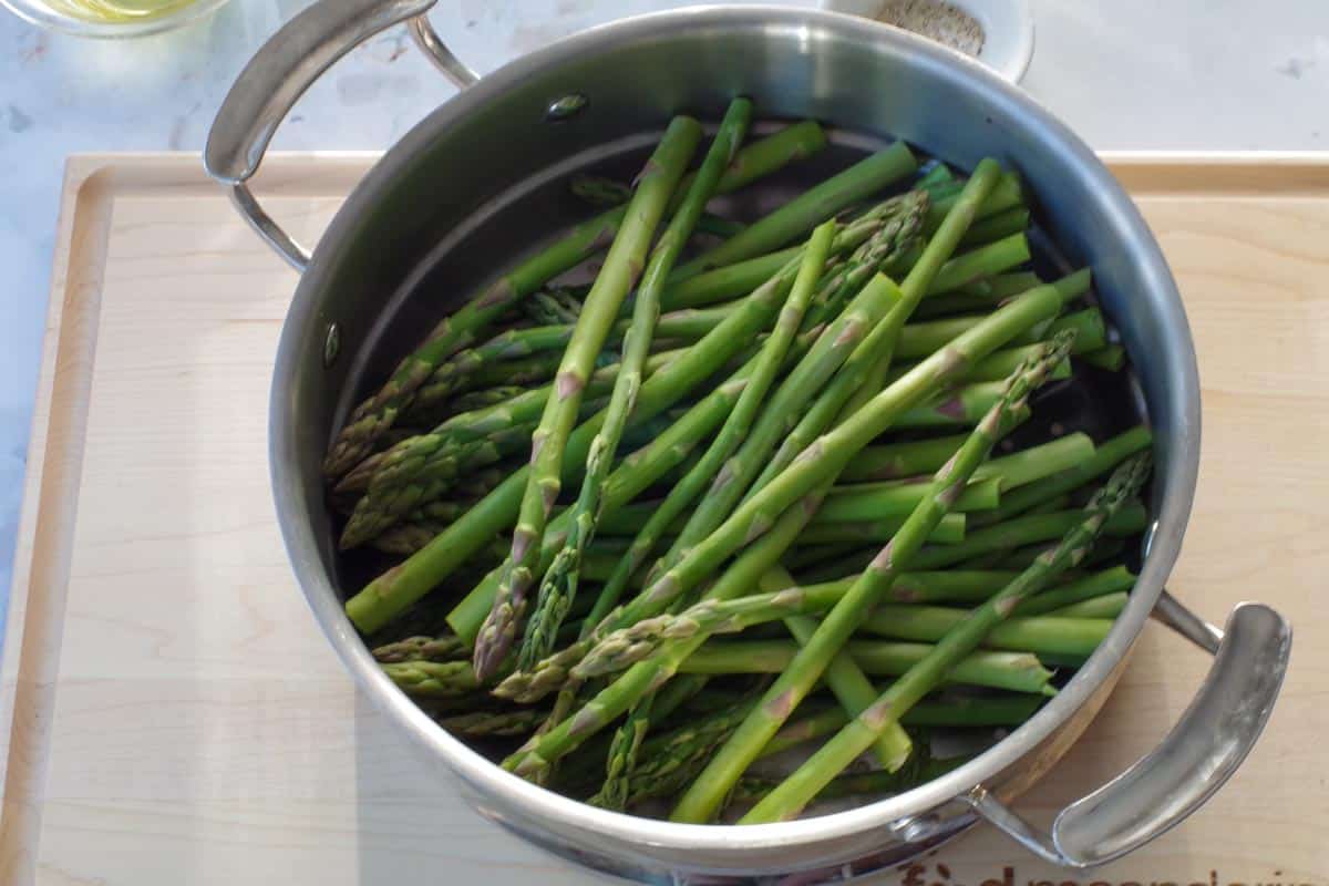 steamed asparagus in a steamer on a cutting board