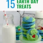 A stack of green and blue Earth Day cookies with a glass container of milk beside it.