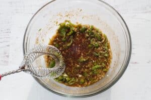 marinade ingredients in glass bowl with metal whisk