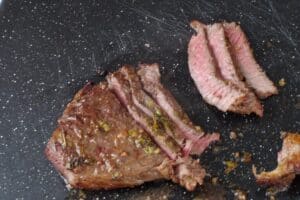 steak being sliced ¼ inch thick on a cutting board