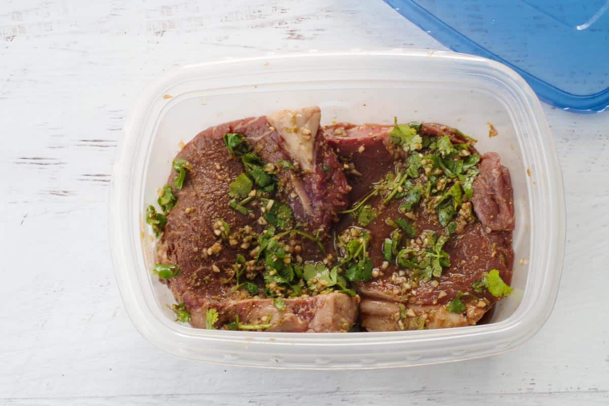 steak with marinade poured over it in a Ziploc container