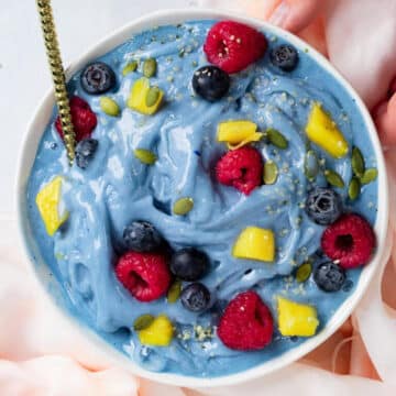 blue smoothie bowl with fruit and a gold spoon