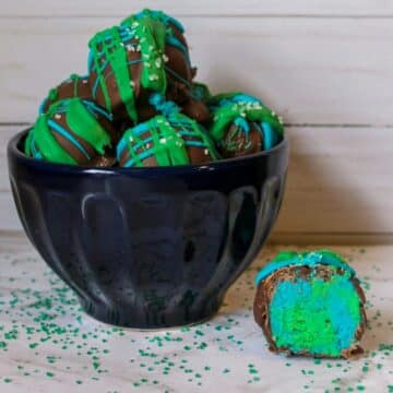 Earth Day Cake Bites in a black bowl with one cake bite (showing insides) beside the bowl