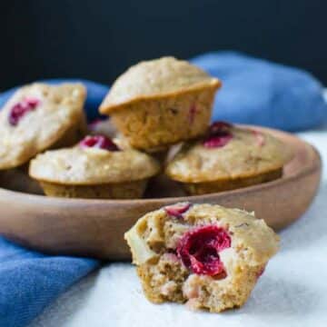 fruit and nut bran muffin with middle of muffin showing and bowl of more muffins in the background