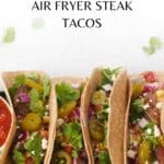 Air fryer steak tacos with a dish of salsa on one side and a dish of sour cream on the other, as well as lime wedges, on a black serving tray