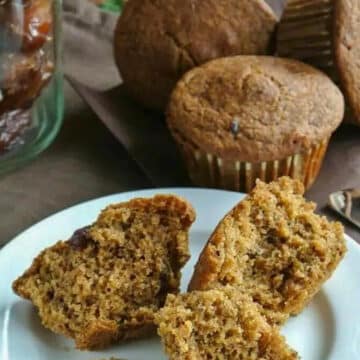 Healthy Date Bran Muffin broken into pieces on white plate with more date bran muffins in the background