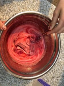 cream and food coloring blended with gelatin mixture in stainless steel bowl