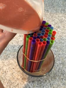 mixture being poured into straws in a glass