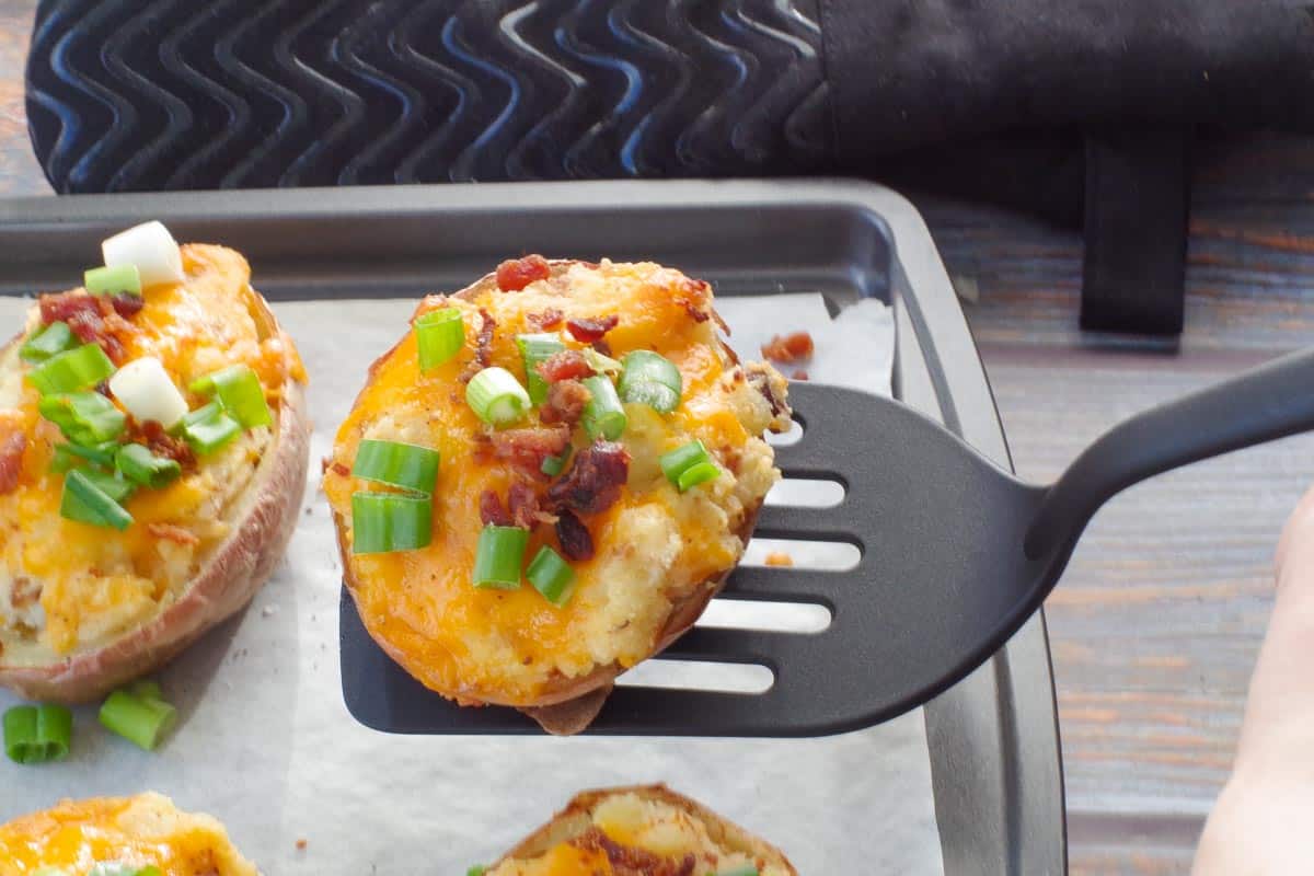 Twice baked potato being lifted off a baking sheet with a spatula
