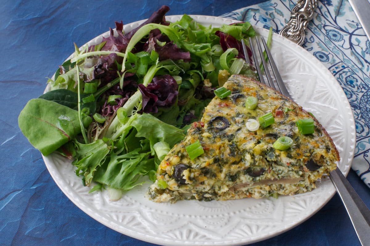slice of ww quiche on a plate with mixed greens