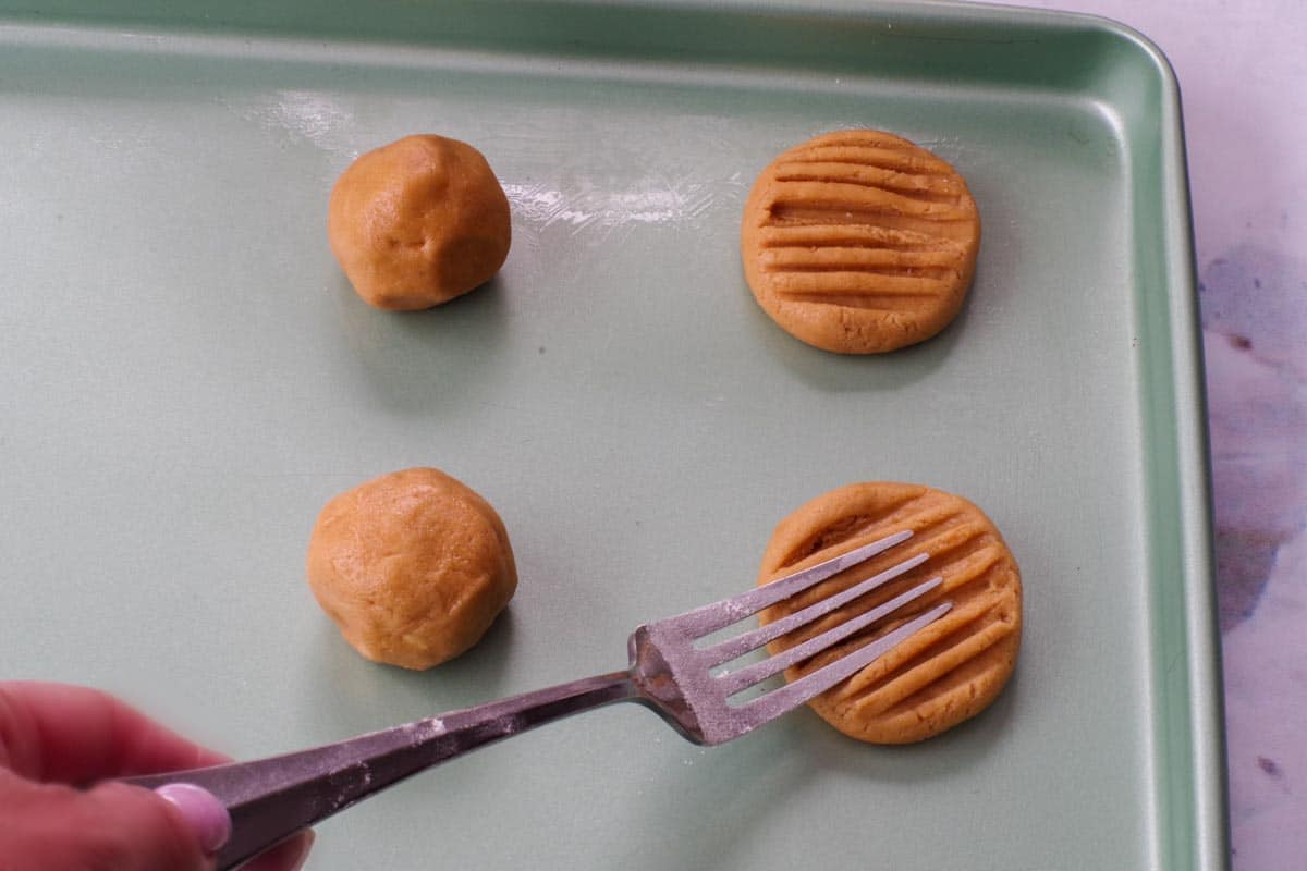 flour dipped fork flattening cookie dough balls