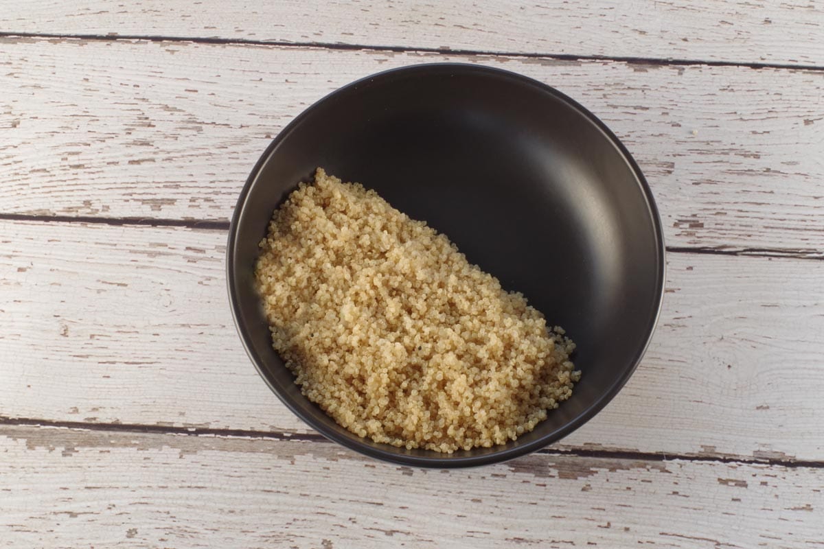 cooked quinoa in black bowl, covering half the surface of the bowl