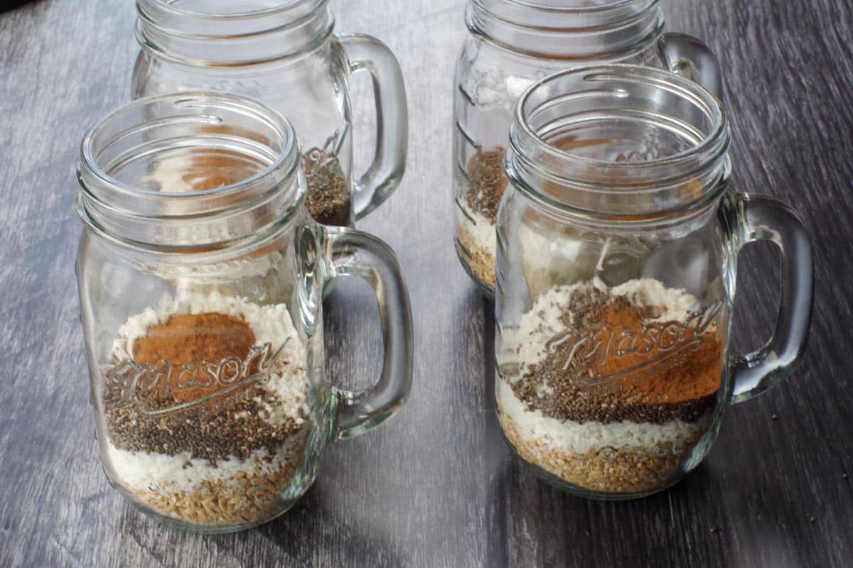 4 mason jar mugs with cinnamon, oats, chia seeds and coconut in them