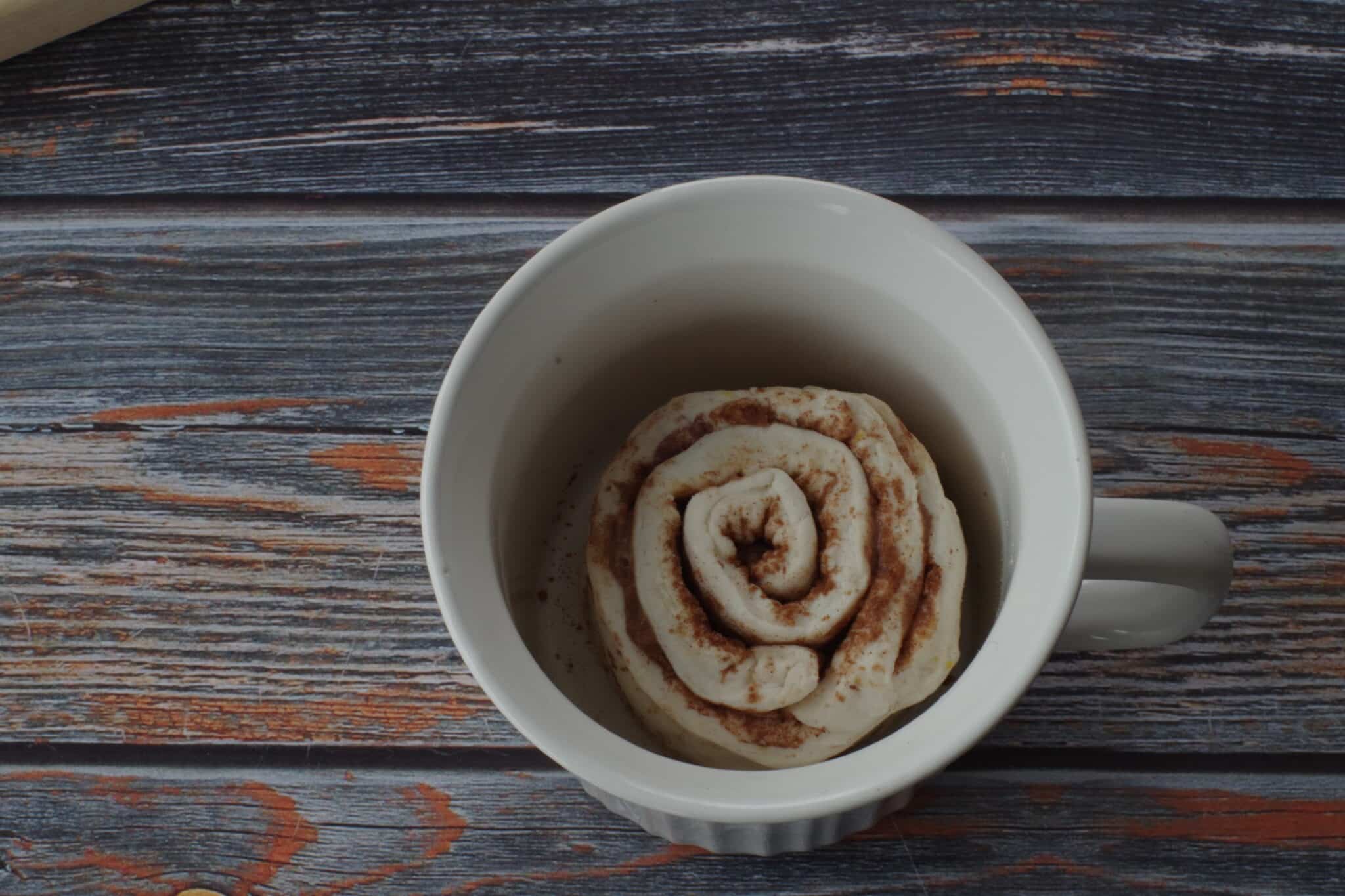 cinnamon roll dough placed inside a meal mug