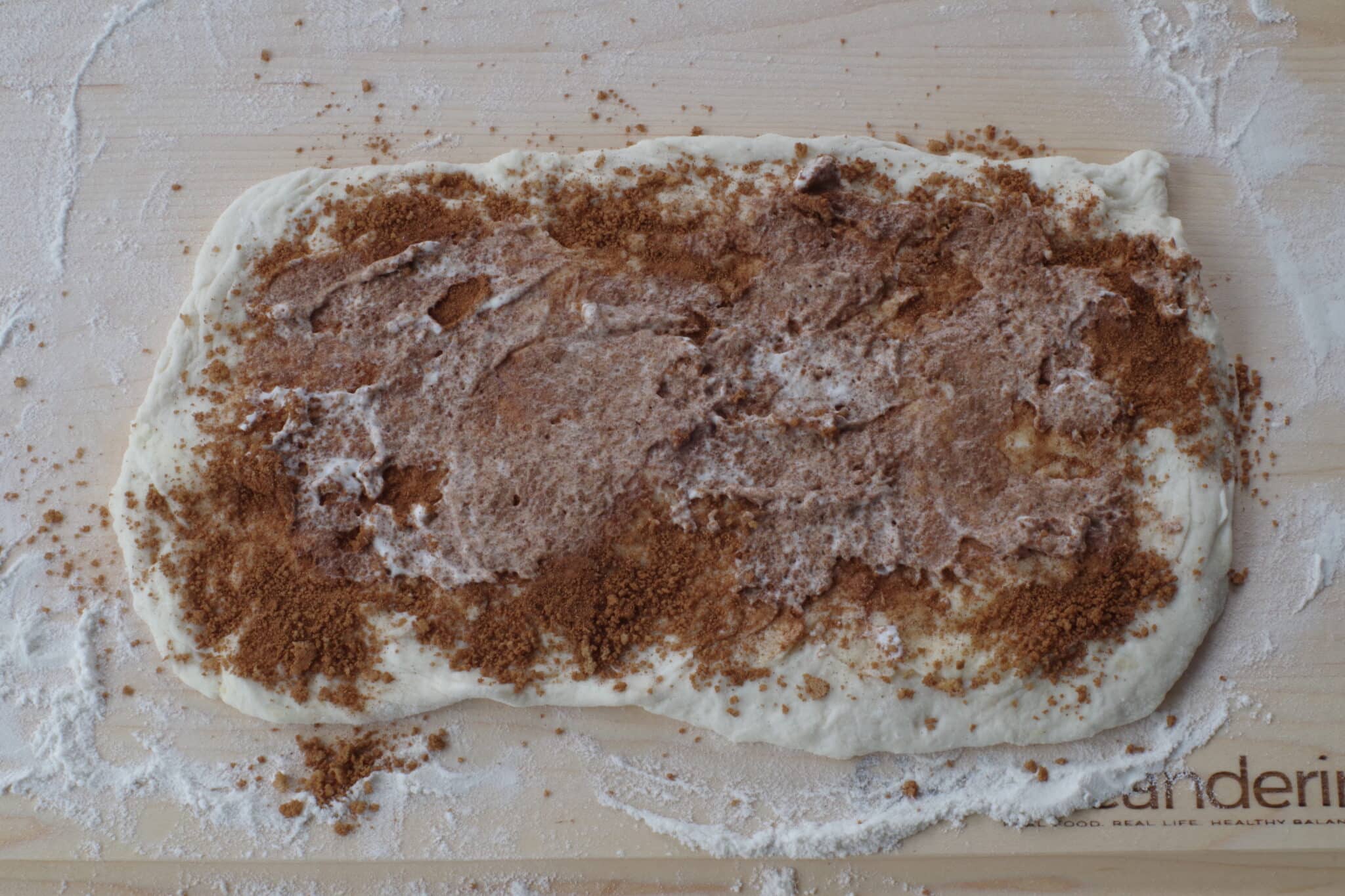 whipped cream spread on brown sugar cinnamon mixture on dough rectangle