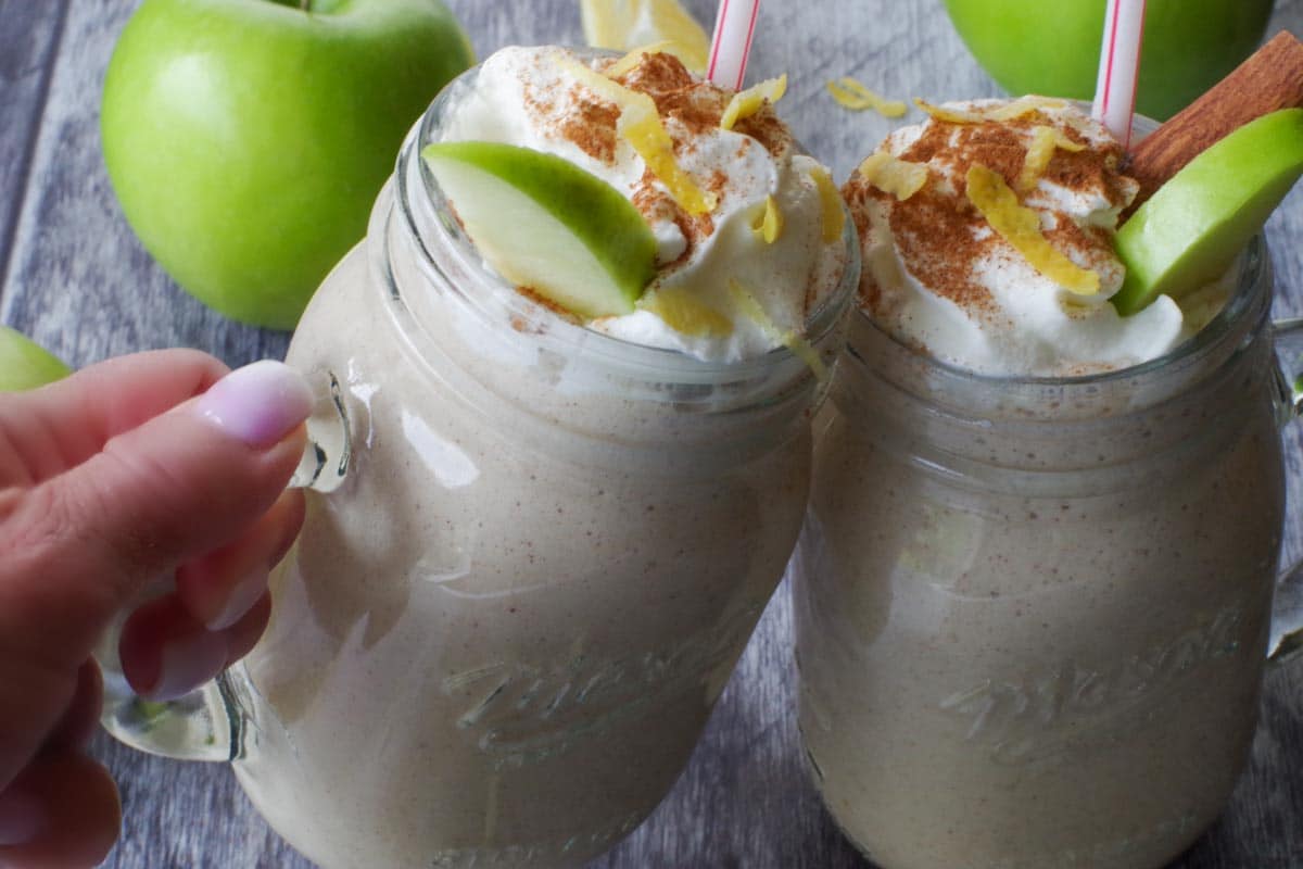 apple pie smoothie in glass mason jars clinking each other