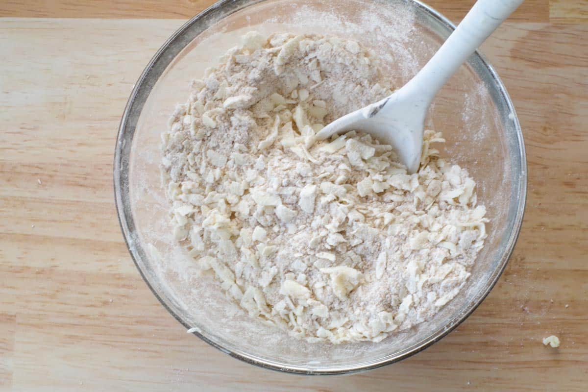 grated butter mixed in glass bowl with dry ingredients
