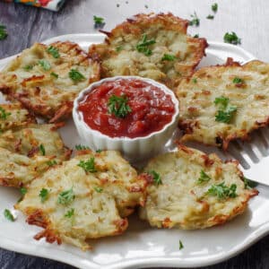 shredded air fryer potato pancakes on a white plate with a white bowl of salsa in the middle