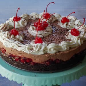 Whole No Bake Black Forest Cheesecake on a turquoise cake stand