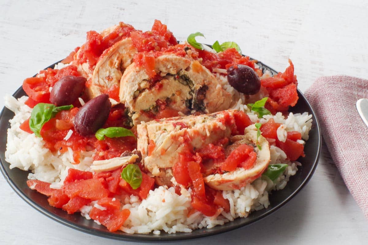 Mediterranean Slow Cooker Stuffed Chicken breast on rice, on a black plate