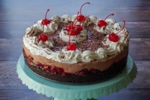 Whole No Bake Black Forest Cheesecake on a turquoise cake stand