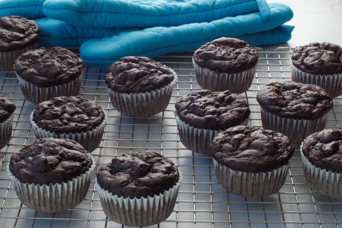 chocolate weight watchers zucchini muffins on cooling rack with blue oven mitt in the background