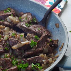 cooked venison steak in a skillet with a spatula turner