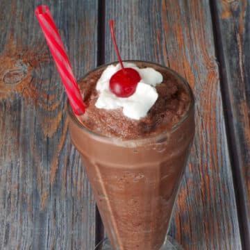 Weight Watchers Chocolate Frosty in a tall soda glass, with a straw and a dollop of whipped cream and a cherry on top