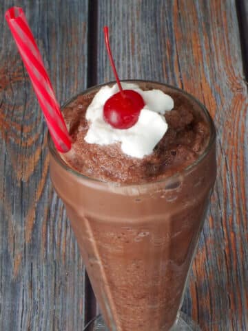 Weight Watchers Chocolate Frosty in a tall soda glass, with a straw and a dollop of whipped cream and a cherry on top