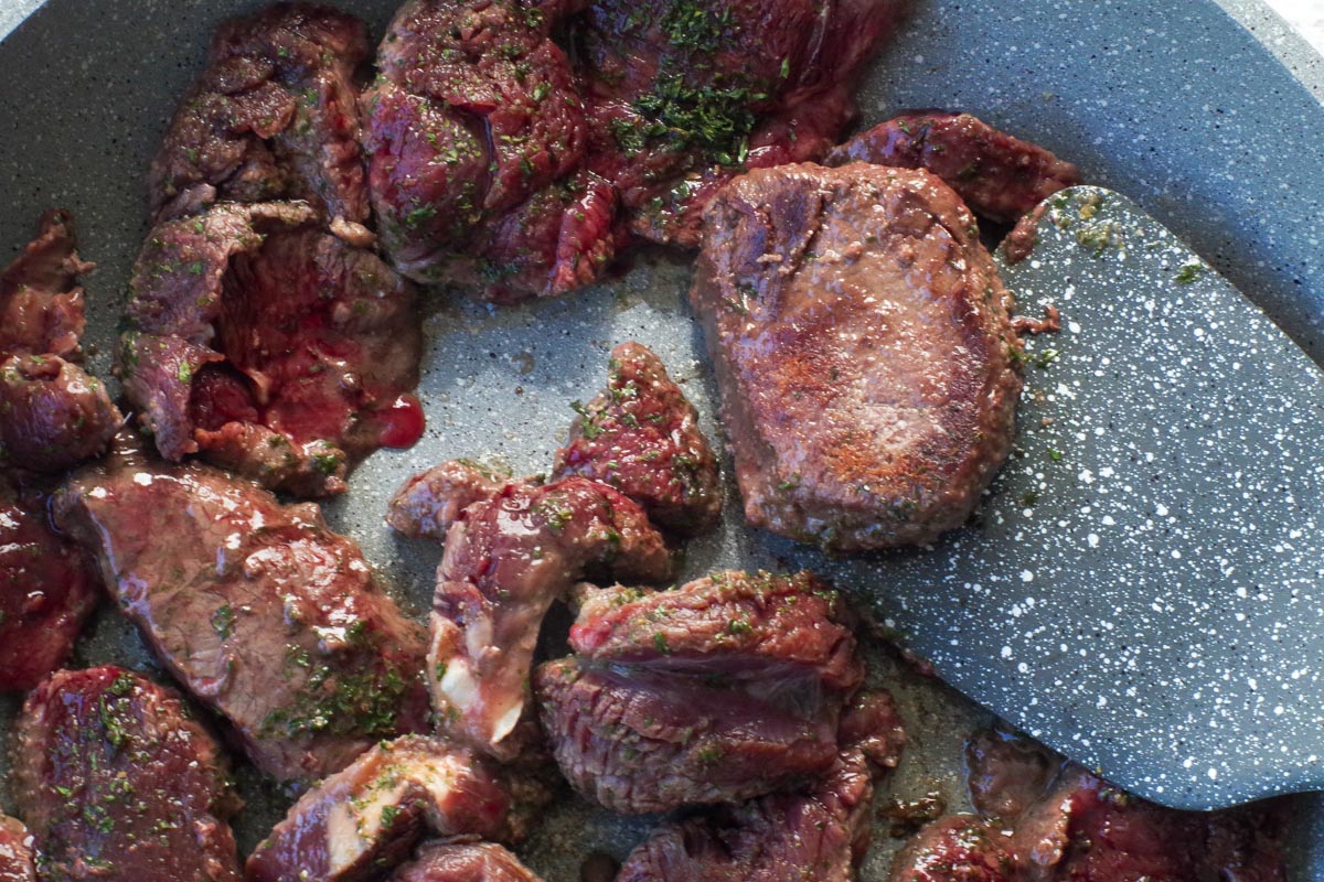 piece of venison steak being held up with a spatula turner