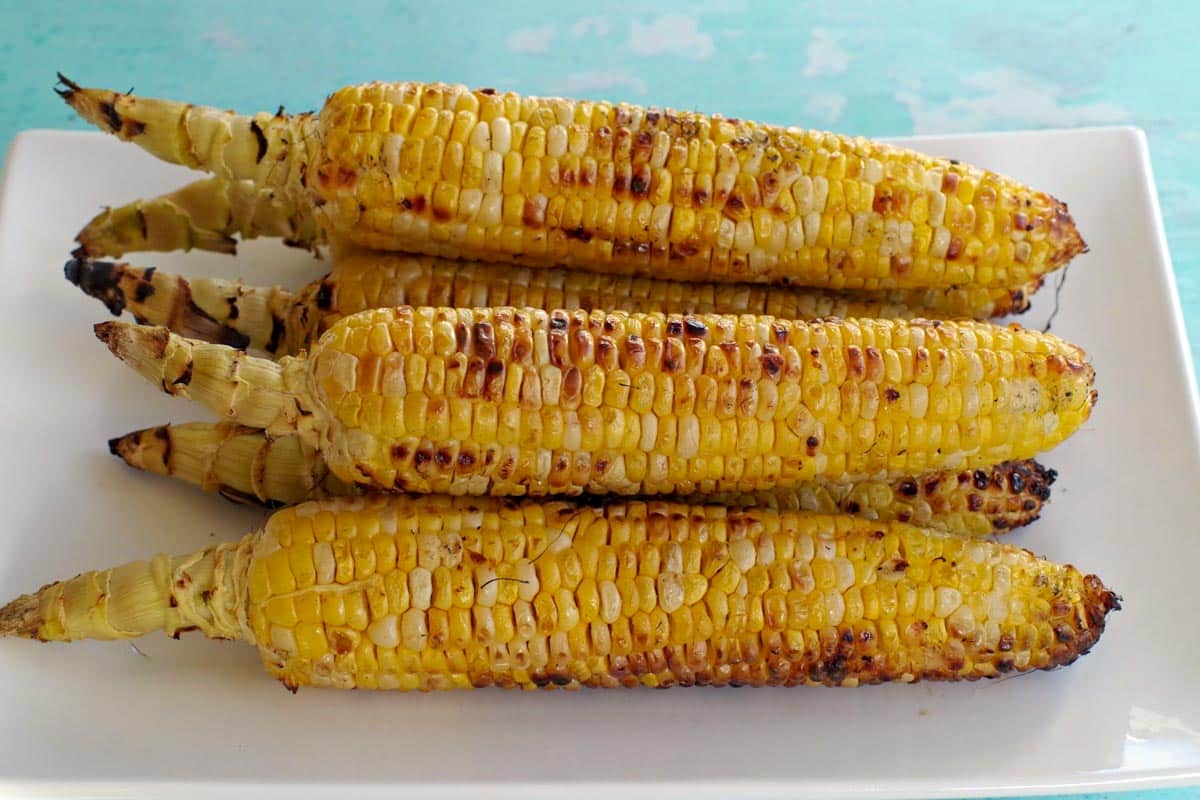 grilled corn on the cob on a white platter