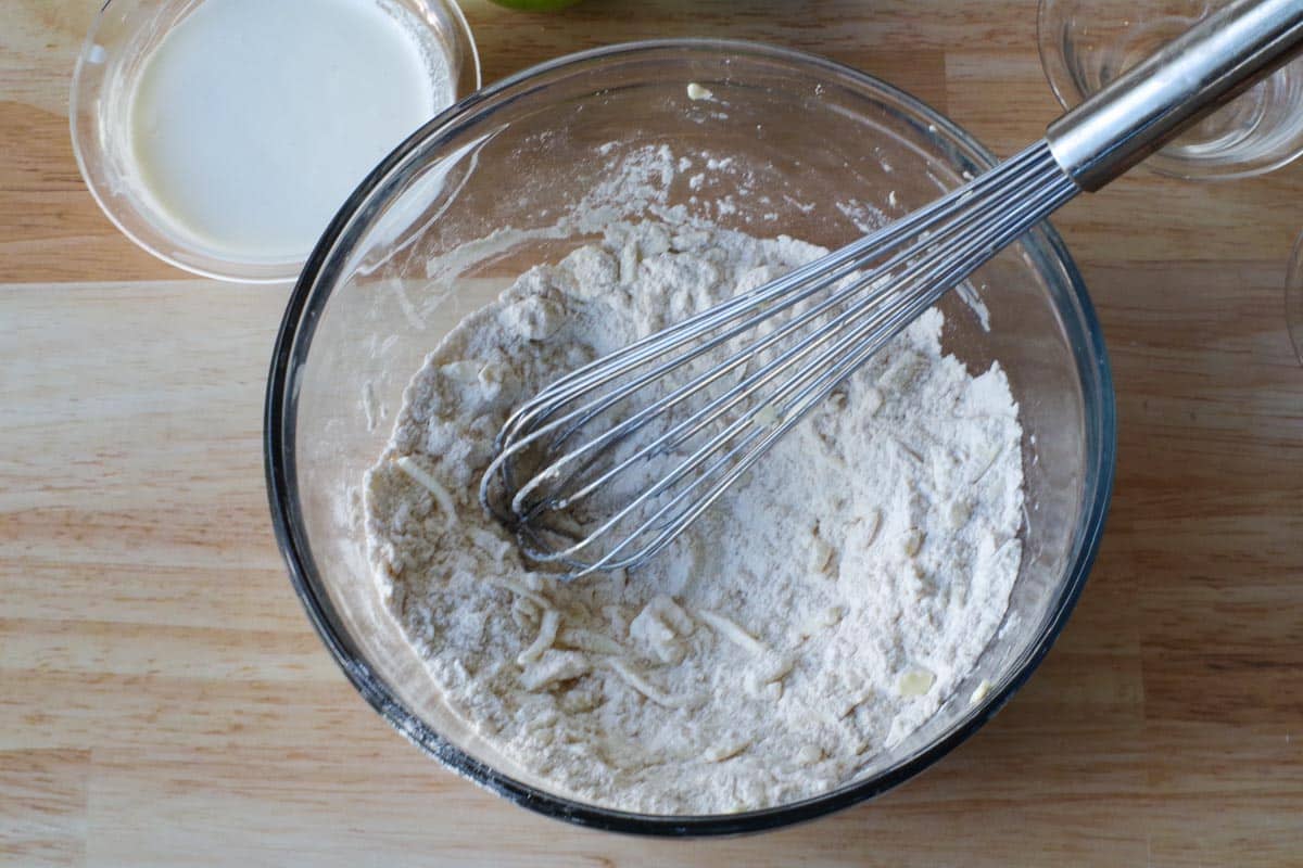 grated butter mixed into dry ingredients in large glass bowl with whisk