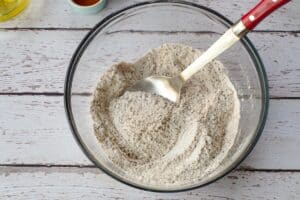 dry ingredients in a large glass bowl with a large metal spoon