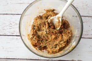 wet ingredients and dry ingredients mixed together in a glass bowl with a marble silicone spoon