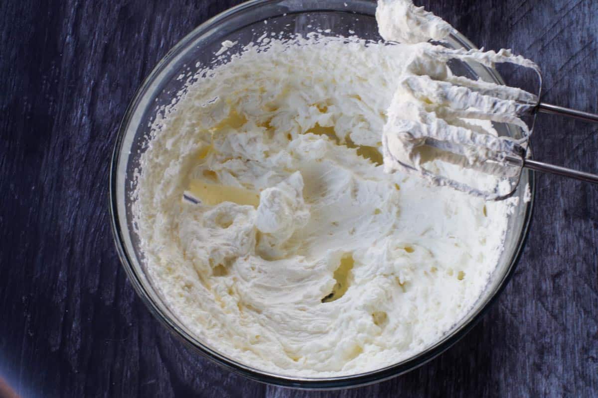 whipped cream beaten to stiff peaks in glass bowl with beaters