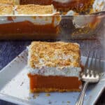 pumpkin layered dessert on a white plate with a fork and more in pan in background