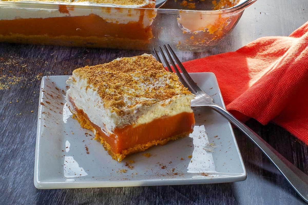 pumpkin layered dessert on a white plate with a fork and more in pan in background