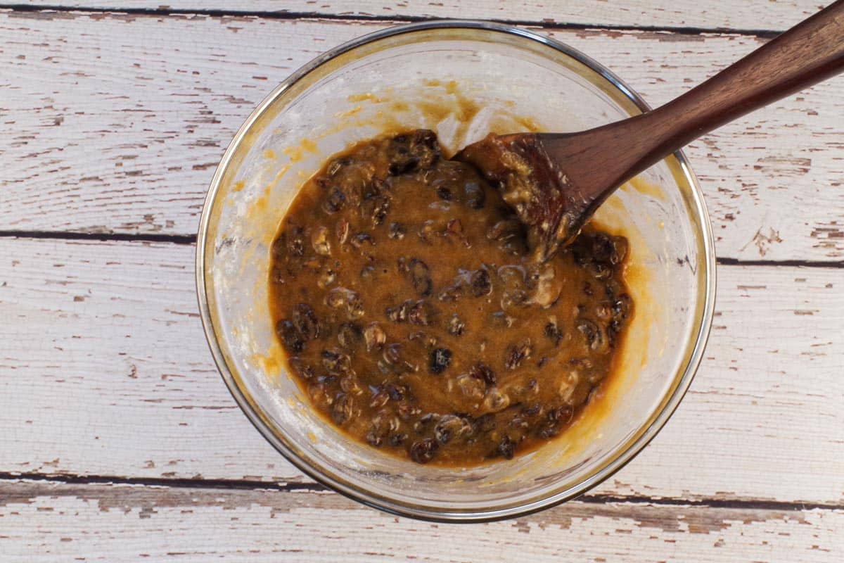 Topping ingredients mixed together in medium glass bowl with dark wooden sppon.