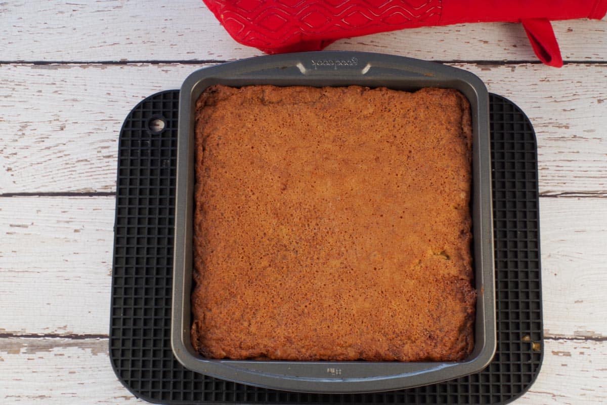 Baked butter tart slice in pan, on a black trivet.