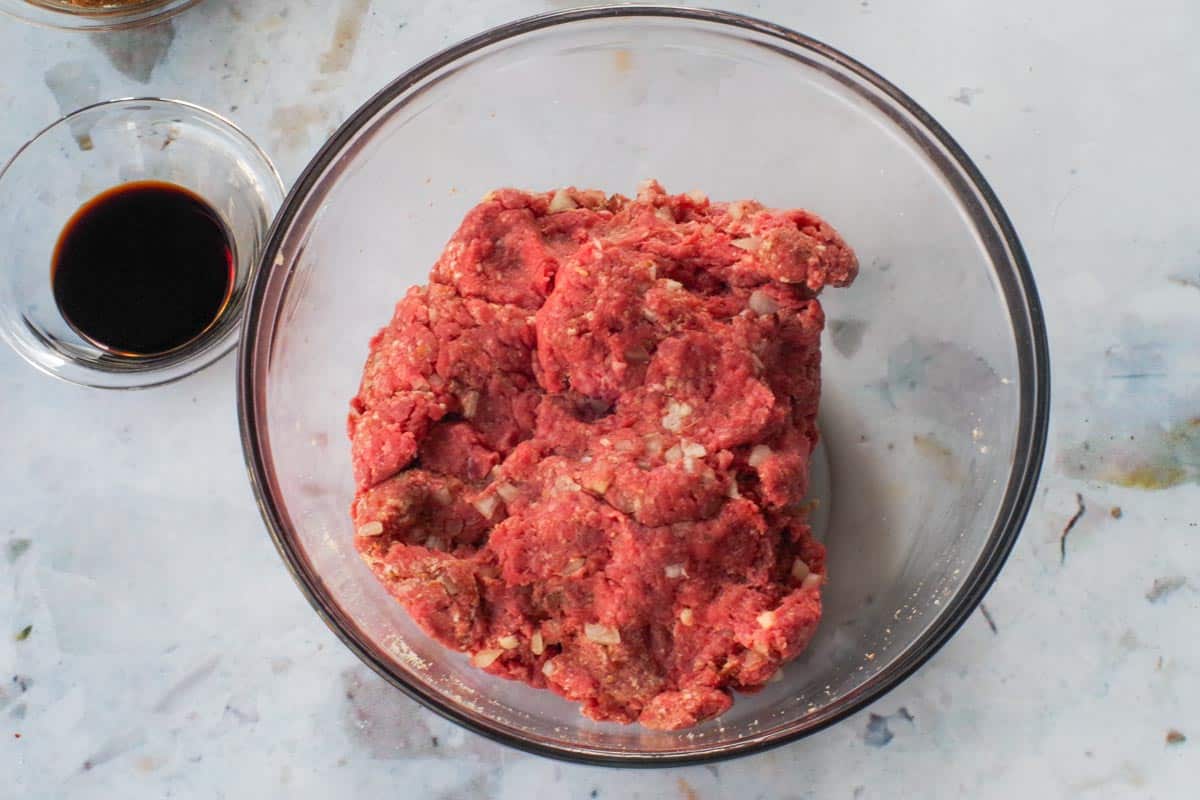 Meatball ingredients mixed together in a large glass bowl.