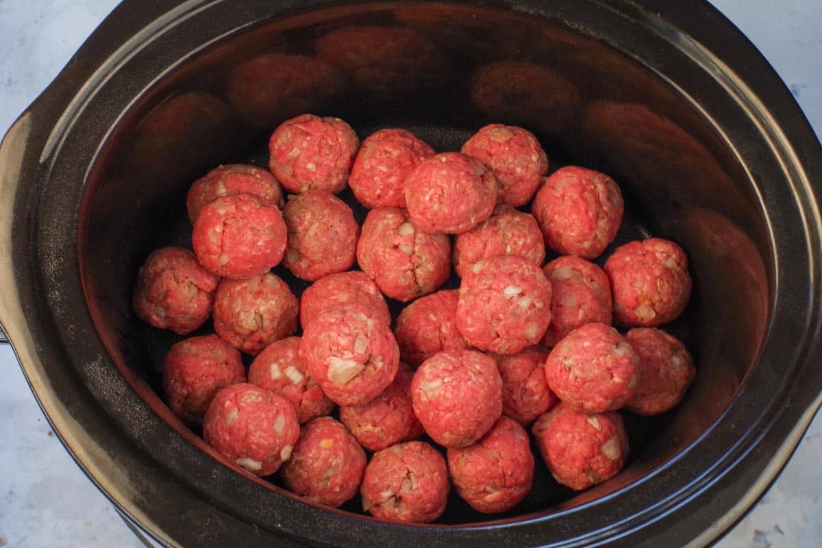 Formed meatballs placed in slow cooker.